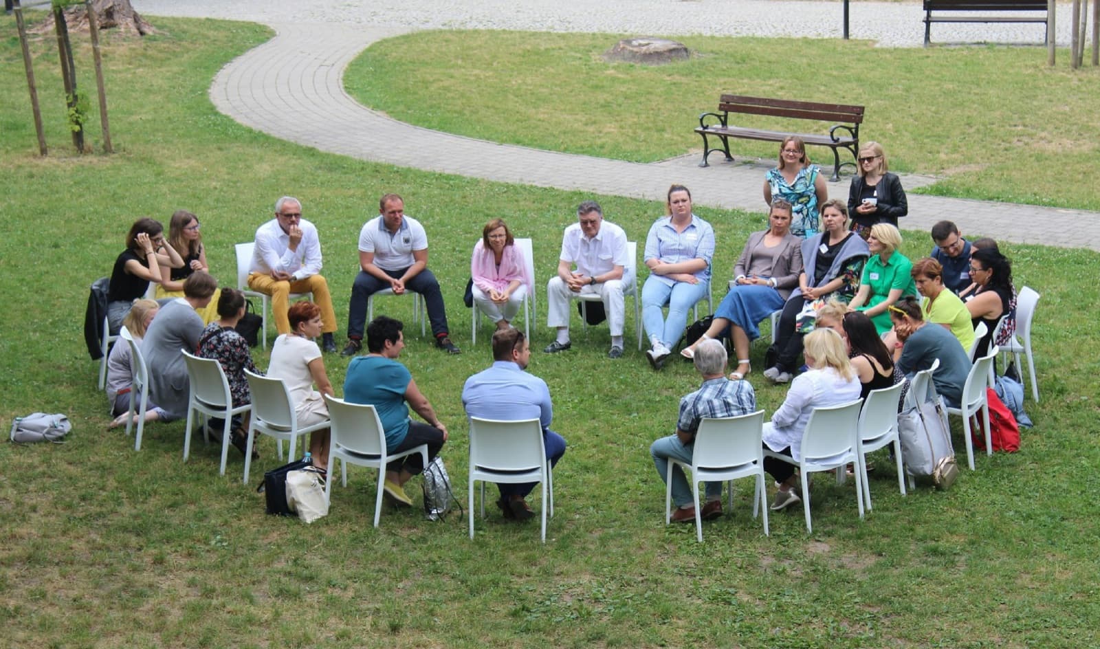 A group of people sitting in a circle outdoors during a training workshop
