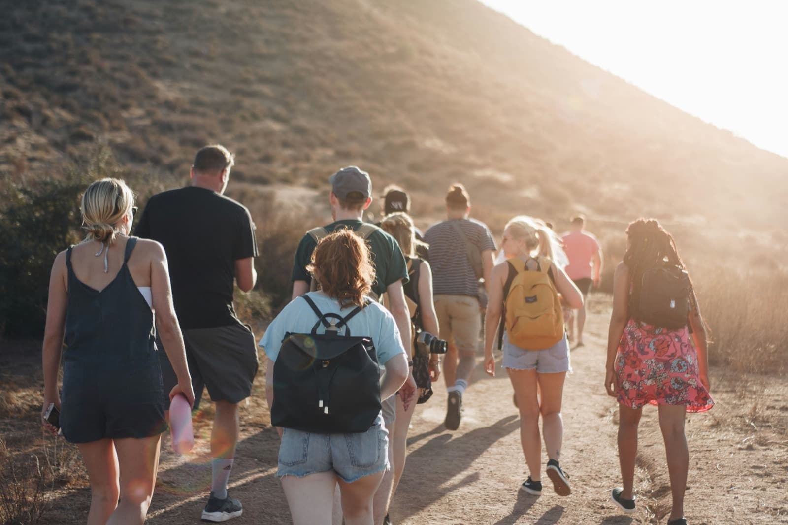 Group of teenagers hiking together on a trail at sunset