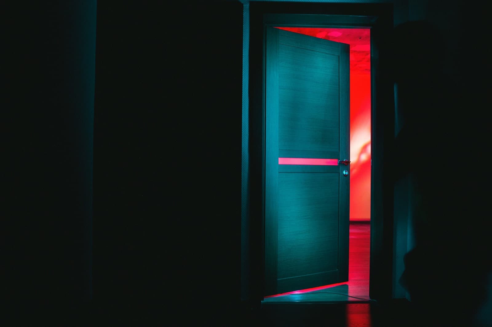 An open door leading from a cool blue-green room into a warm red room, inviting you in