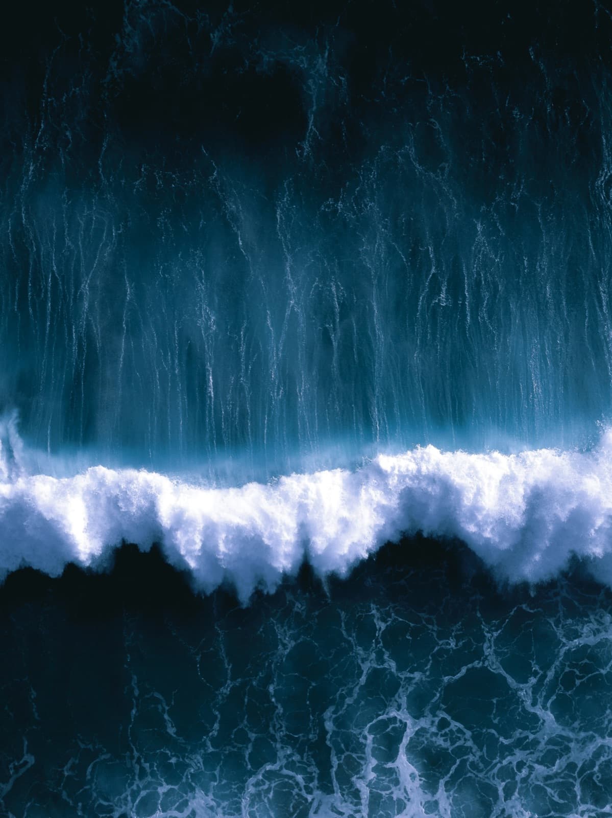 Aerial view of a wave breaking between dark water