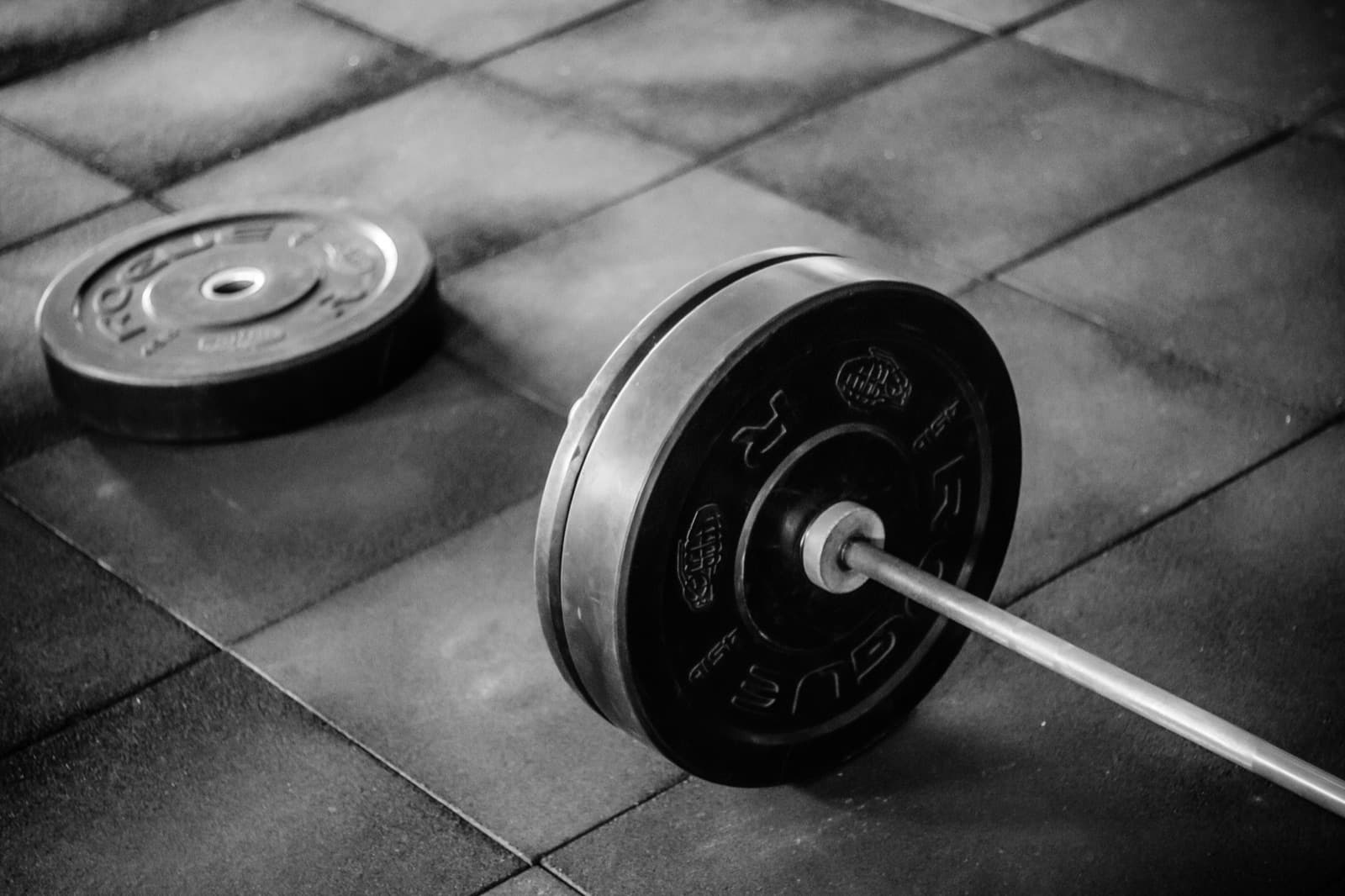 A barbell with weights resting on the floor — training means doing the work