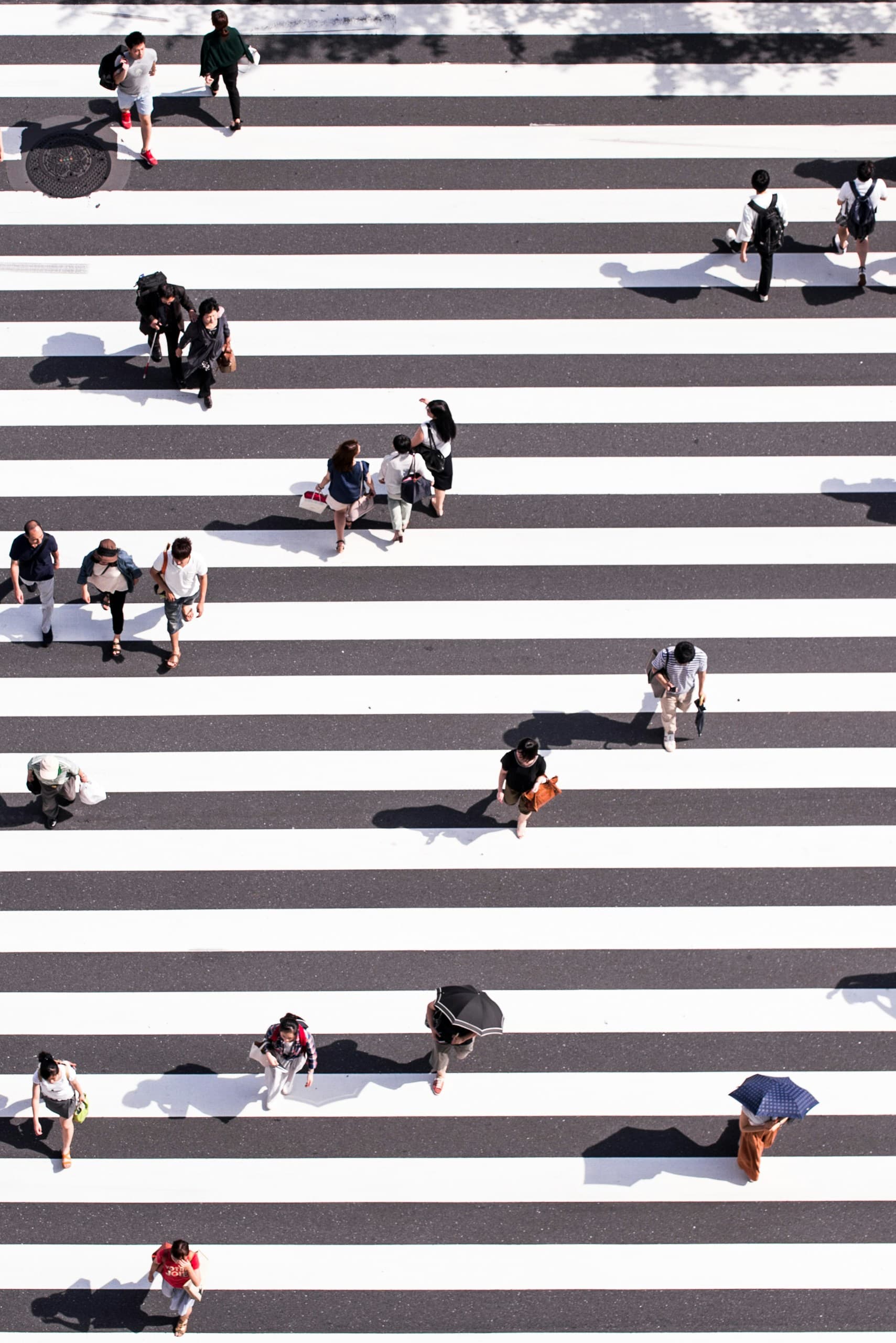 Aerial view of people walking across striped crosswalk — the interpersonal patterns we explore in process groups